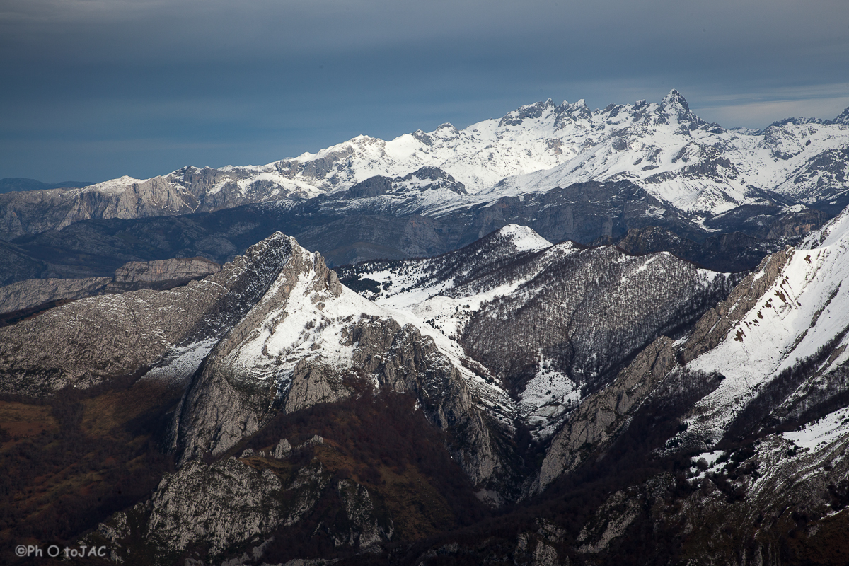 Vistas desde la cima. A la izquierda se ve la curiosa forma del Recuencu y al fondo los Picos de Europa, con la emblemática Peña Santa de Castilla a la derecha.